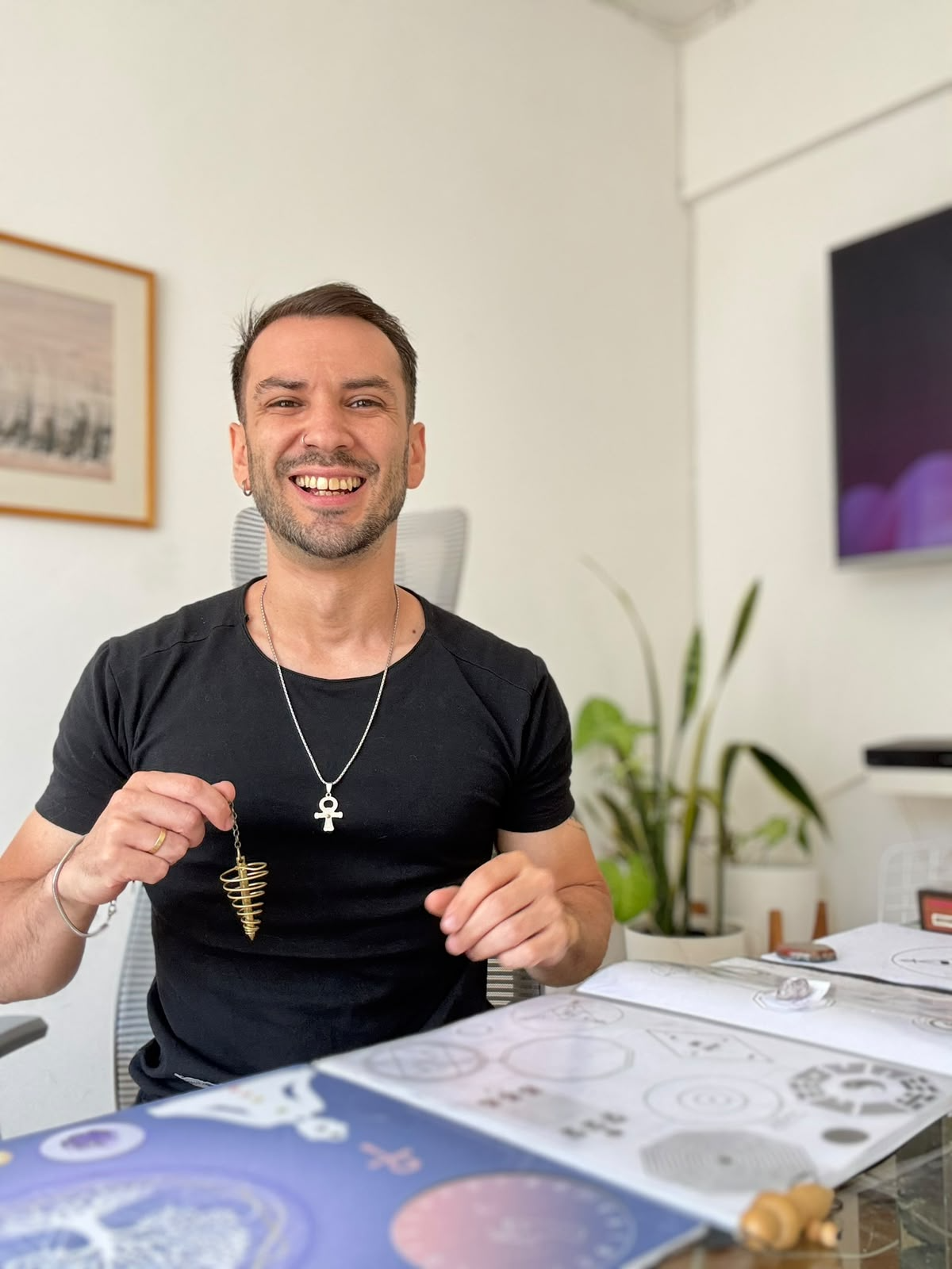 Cristian de Vuelo Sonoro, sonriendo con un péndulo en su espacio de trabajo